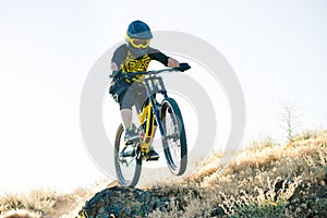 Cyclist Riding the Mountain Bike on the Summer Rocky Trail at the Evening. Extreme Sport and Enduro Cycling Concept.