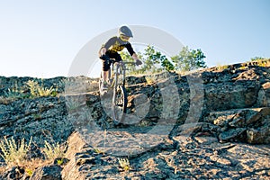 Cyclist Riding the Mountain Bike on the Summer Rocky Trail at the Evening. Extreme Sport and Enduro Cycling Concept.