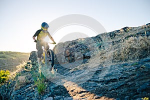 Cyclist Riding the Mountain Bike on the Summer Rocky Trail at the Evening. Extreme Sport and Enduro Cycling Concept.