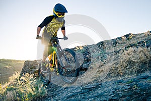 Cyclist Riding the Mountain Bike on the Summer Rocky Trail at the Evening. Extreme Sport and Enduro Cycling Concept.