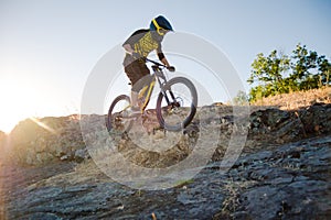 Cyclist Riding the Mountain Bike on the Summer Rocky Trail at the Evening. Extreme Sport and Enduro Cycling Concept.