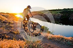 Cyclist Riding the Mountain Bike on the Summer Rocky Trail at the Evening. Extreme Sport and Enduro Cycling Concept.