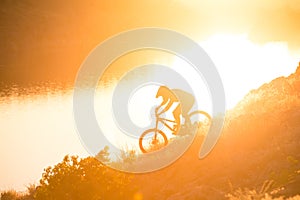 Cyclist Riding the Mountain Bike on the Summer Rocky Trail at the Evening. Extreme Sport and Enduro Cycling Concept.