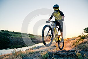 Cyclist Riding the Mountain Bike on the Summer Rocky Trail at the Evening. Extreme Sport and Enduro Cycling Concept.