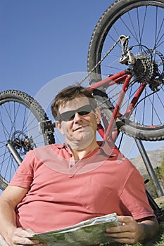 Cyclist With Roadmap Lying In Front Of Bicycle Upside Down