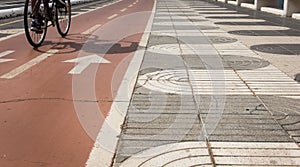 Cyclist shadow on bicycle red lane next to pedestrian sidewalk