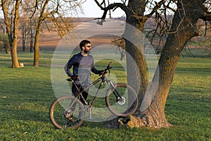 Cyclist in shorts and jersey on a modern carbon hardtail bike with an air suspension fork standing on a cliff against the backgrou photo