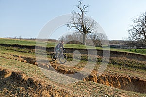 Cyclist in shorts and jersey on a modern carbon hardtail bike with an air suspension fork standing on a cliff against the backgrou