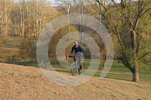 Cyclist in shorts and jersey on a modern carbon hardtail bike with an air suspension fork standing on a cliff against the backgrou