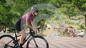 Cyclist struggling on bicycle during intense cycling workout training. Female professional cyclist riding bike on bicycle lane, ha