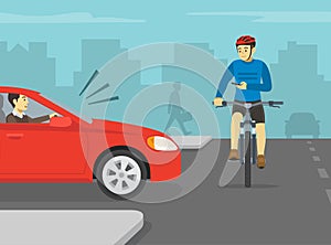 Cyclist is about to be hit by red sedan car while looking at phone on city road. Using a mobile phone while bicycle riding.