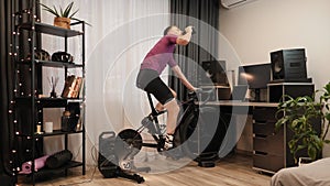 Cyclist is training on indoor smart bicycle trainer at home. Fitness cardio workout. Male athlete is doing exercises on stationary