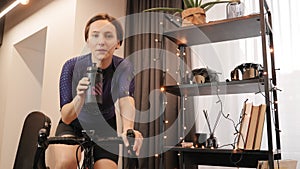 Cyclist is training on smart bike trainer, preparing for online cycling races. Indoor cycling. Home sport activity. Woman is cycli