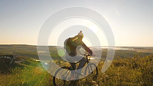 Cyclist travels on top of mountain in park in morning at sunrise of sun. The free young man traveler rides his bike to