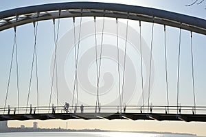 Cyclist and walker in silhouette on Humber Bay Arch Bridge
