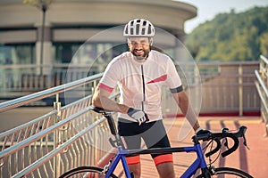 Cyclist with white-toothed smile standing with bicycle