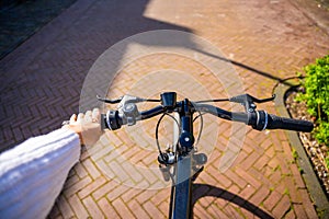 Cyclist woman riding in a sunny summer park, first-person view