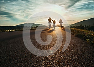 Cyclists family traveling on the road at sunset