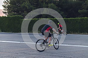 Cyclists ride, dressed up with red and black cloths on country roads on a evening in Spain