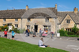 Cyclists and walkers outside the Old Post Office on the green in the Cotswolds