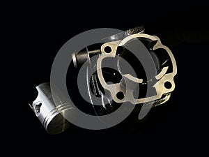 Cylinder and piston on a black background. Piston system from a moped. Motor parts from a motorcycle