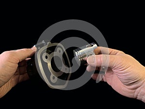 Cylinder and piston in a hand, on a black background. Piston system from a moped. Parts of a motor from a motorcycle, closeup