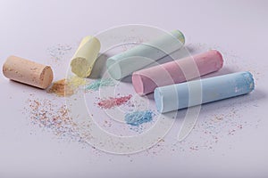 Cylindrical colored chalks, partially crumbled, on a white background