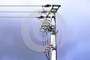 Cylindrical concrete electric pole with high voltage electrical cables and ceramic isolators.