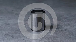 A cylindrical metallic object with a black top sits on a gray surface.