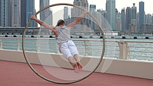 Cyr Wheel artist in slow motion with cityscape background of Dubai during sunrise