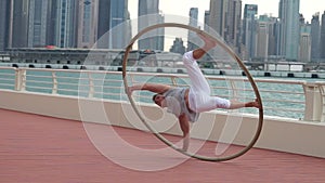 Cyr Wheel artist in slow motion with cityscape background of Dubai during sunrise