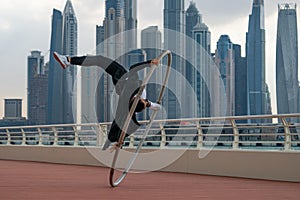 Cyr Wheel artist wearing black and white smart clothes with cityscape background of Dubai during sunset