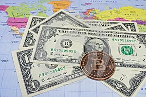 Close up physical bitcoin coin with US dollars and world map.
