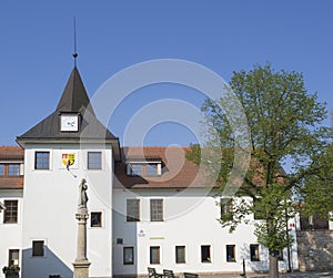 Czech Republic, Prague, Dolni Pocernice, April 21, 2018: old village Town hall with tower clock and stone staue, green tree and