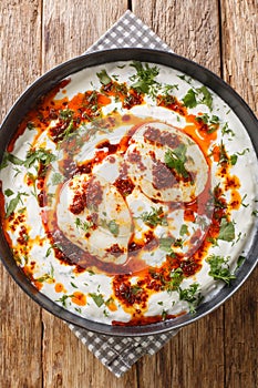 CÃÂ±lbÃÂ±r is a Turkish dish of poached eggs with yogurt closeup in the plate. Vertical top view photo