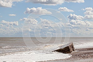 D-day Normandy landings. Coastal landscape with clouds and partially buried WW2 beach defense building.