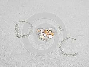 D heart`s C initials on sand with heart filled in with seashells