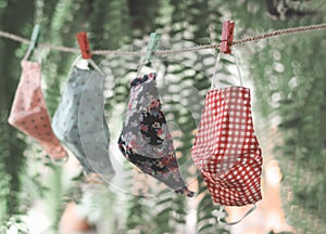 D.I.Y colorful fabric face masks hanging after washing for reuse. on green garden and bokeh background.protection from coronavirus