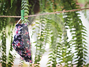 D.I.Y flower pattern  fabric face masks hanging after washing for reuse on green garden and bokeh background.protection from