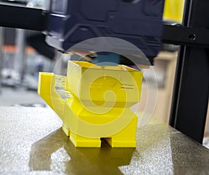 3D printer prints an object. The process of printing yellow model on 3D printer
