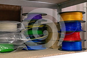 3D printing material, ABS filament, PLA & x28;Polylactic Acid& x29;,  PVA Filament.  Colored polymer in coils on the shelves photo