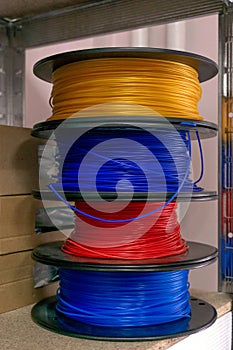 3D printing material, ABS filament, PLA & x28;Polylactic Acid& x29;,  PVA Filament.  Colored polymer in coils on the shelves photo