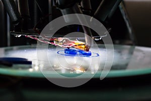 3d printing process close up. Automatic three dimensional 3d printer mechanism prints polymer blue part, component. Three