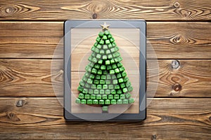 Christmas tree made of computer keys and tablet computer on wooden background. 3d rendering photo