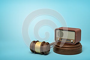 3d rendering of retro radio set on sounding block with brown gavel lying beside on light-blue background with copy space photo