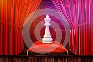 3d rendering of a White king chesspiece on a red royal pillow placed on stage with red curtains. photo
