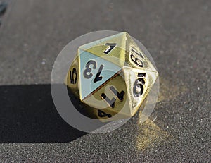 D20 twenty-sided golden metallic die dice on foam background in bright sunshine - 1 on top face