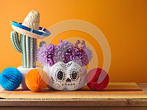Da de los Muertos day of the dead holiday concept. Sugar skull Halloween pumpkin and Mexican party decorations on wooden table