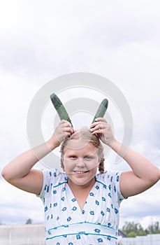 At the dacha, a girl holds fresh green cucumbers in her hands.