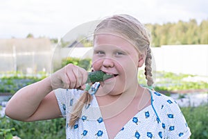 At the dacha, a girl holds fresh green cucumbers in her hands.